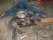 1985 Ford Crown Victoria LTD - Disassembled engine components are laid out on a concrete floor next to a vehicle lift.