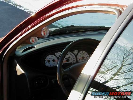 1997 Ford Taurus interior showing dashboard gauges and two aftermarket gauges on the A-pillar
