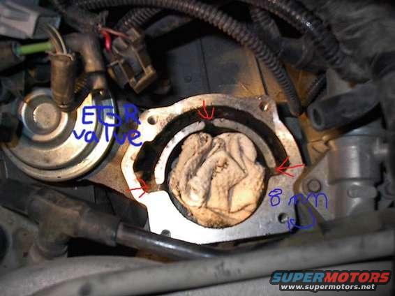EGR valve with a rag stuffed into the opening, marked with red arrows and blue writing