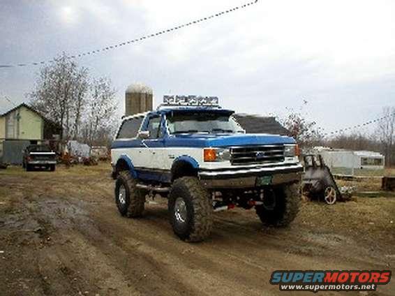 Lifted 1990 Ford Bronco, blue and white, with off-road lights on the roof visor