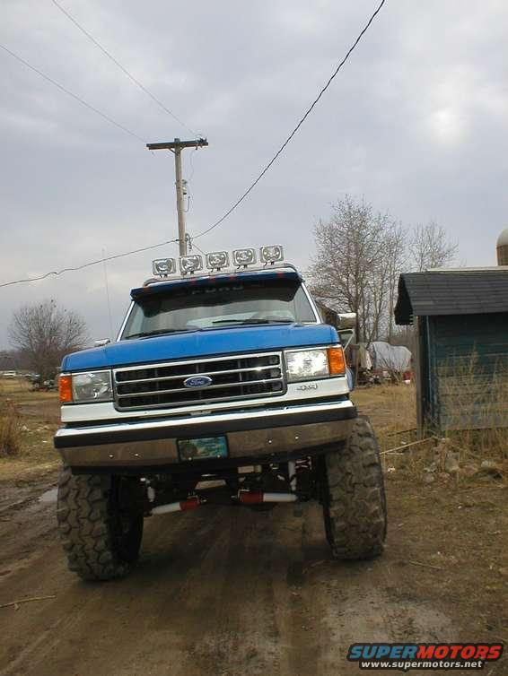 Blue 1990 Ford Bronco front view with large tires and light bar