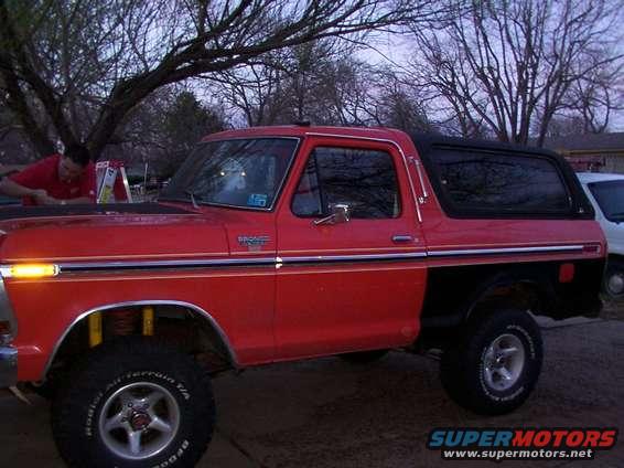 Red Ford Bronco with black trim and a black hardtop, parked outside