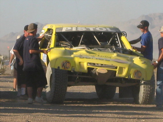 Yellow off-road racing truck with "PISTOL" on windshield, "American Racing" on hood, and KC logos