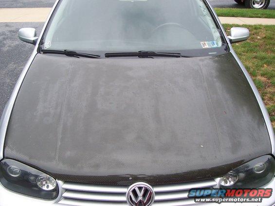 Volkswagen hood with carbon fiber wrap, showing headlights and grille emblem