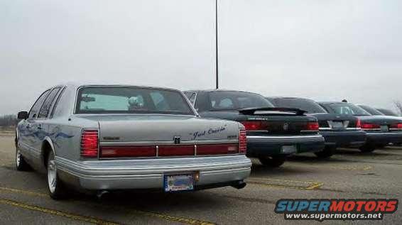 Silver sedan with blue flame decals and 'Just Cruise' script on trunk, parked in a lot with other sedans