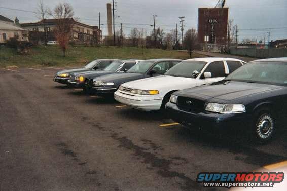Four Ford Crown Victoria police cars parked in a lot, front view