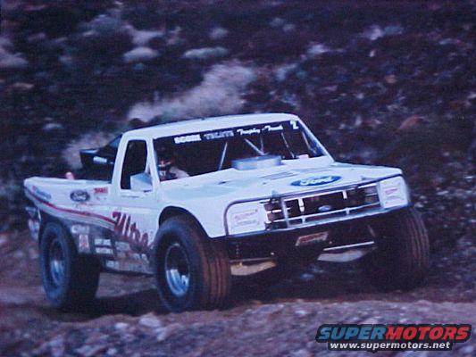 White off-road racing truck with "Ultra" graphics, front grille visible