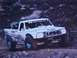 1984 Ford Bronco - This modified Ford truck, likely from the late 1980s, competes in an off-road race.