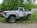 1984 Chevrolet Blazer - This lifted pickup truck appears to be from the 1970s, with a missing grille and a spare tire in the bed.