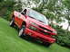2008 Chevrolet Colorado - A red Chevrolet Colorado pickup truck is angled on a grassy hill with trees in the background.