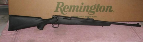 Black Remington rifle on a pink cloth with a Remington box behind it
