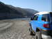 2007 Toyota FJ Cruiser - A blue 2007 Toyota FJ Cruiser sits parked on a dry lake bed with mountains in the background.