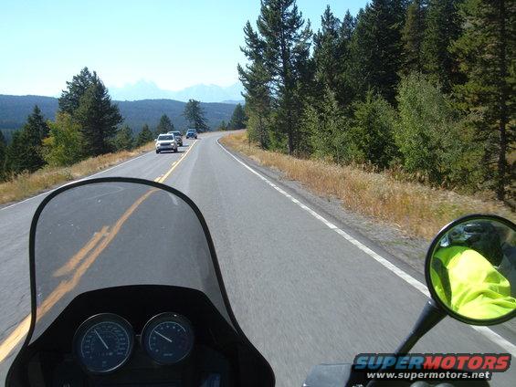 Motorcycle dashboard with two gauges, windshield, and view of road ahead with other vehicles