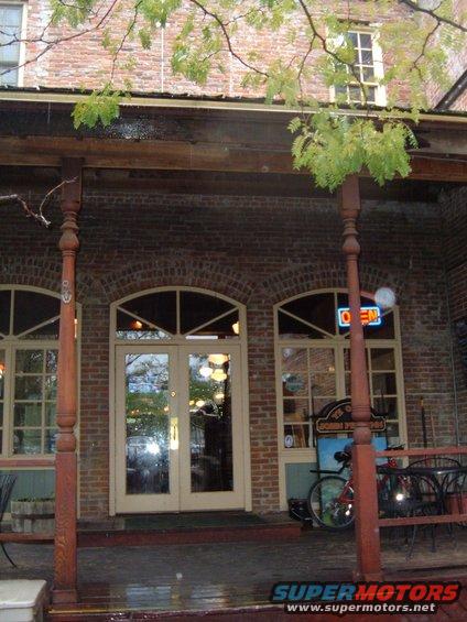 Motorcycle parked on a porch next to a building with arched windows