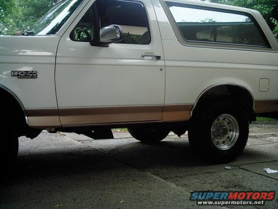 White Ford Bronco with tan trim, side view, parked on concrete