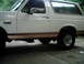 1995 Ford Bronco - Side view of a white Ford Bronco with tan lower trim and tinted windows.