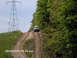 1995 Ford Bronco - A white van navigates a steep, muddy incline under a bright sky, with a large power transmission tower visible on the left.