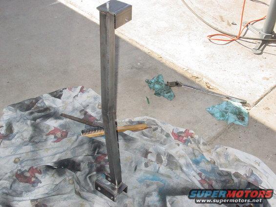 Metal bracket with bolts on a patterned cloth with a brush and oily rags