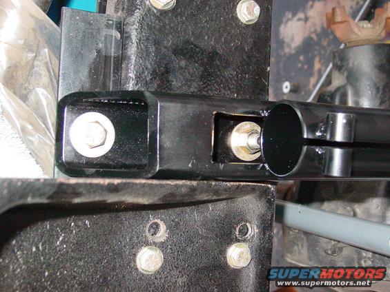 Close-up of a black metal suspension component with bolts