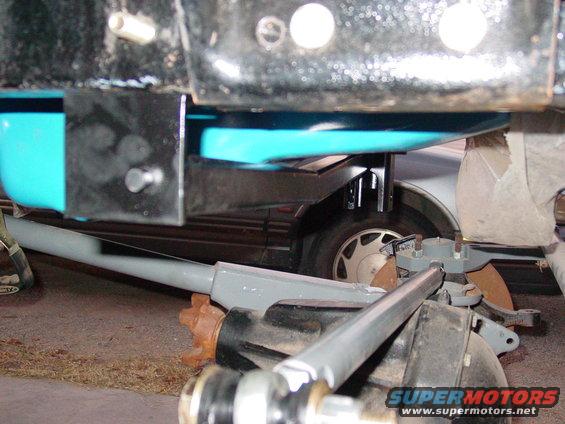 Close-up of a vehicle's front suspension components, including a grey control arm and differential