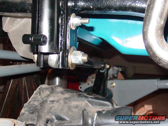 Close-up of vehicle suspension parts including a shock absorber, bolts, and brackets
