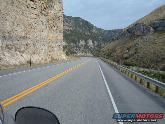 Motorcycle windshield view of a winding road through a mountain canyon