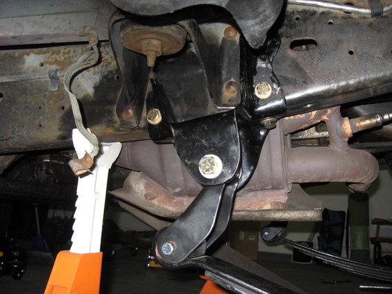 Close-up of vehicle frame with suspension parts and exhaust system, supported by jack stands