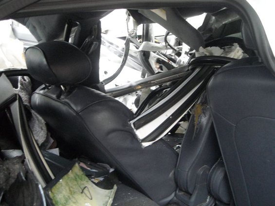Interior of a wrecked car showing torn metal, exposed wires, and damaged seats
