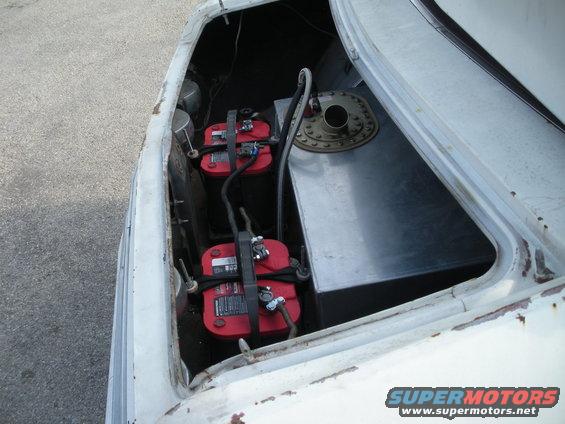 Car trunk with two red Optima batteries and a metal fuel cell. The car is white and appears to be older