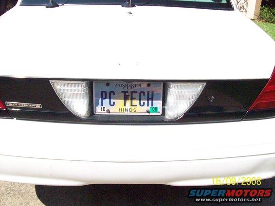 Rear of a white 2003 Ford Crown Victoria police interceptor with a Mississippi license plate reading 'PC TECH'