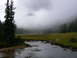 2006 Ford E350 - A foggy mountain scene with a stream flowing through a grassy meadow.