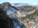 2006 Ford E350 - A wide river cuts through a snow-dusted canyon landscape, bordered by pine trees and distant mountains.