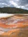 2006 Ford E350 - A natural landscape a steaming geothermal pool with vibrant mineral deposits and a distant tree-covered hill.