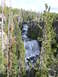 2006 Ford E350 - A scenic view of a waterfall flowing through a forest landscape with rocky cliffs and pine trees.