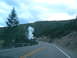 2006 Ford E350 - A road winds through a forested area with a plume of steam rising from a geothermal vent.