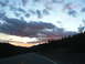 2006 Ford E350 - A highway stretches towards the horizon under a sky filled with dark, dramatic clouds tinged with pink.