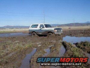 White Ford Bronco stuck in mud, 3/4 front view