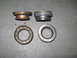 1991 Ford Bronco - Four automotive wheel bearings and seals are displayed on a concrete surface. One bearing shows significant wear.