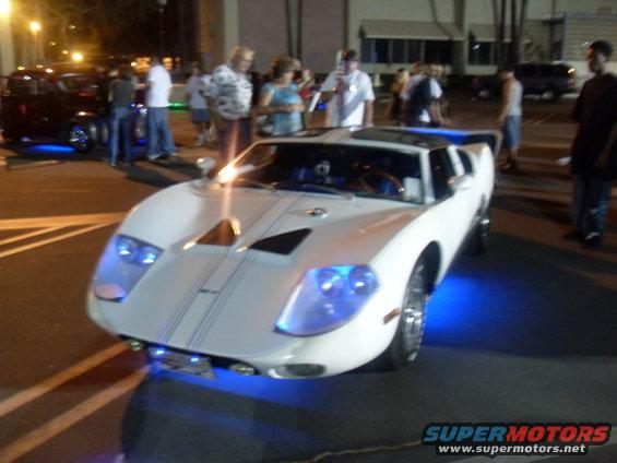 White sports car with blue underglow and racing stripes