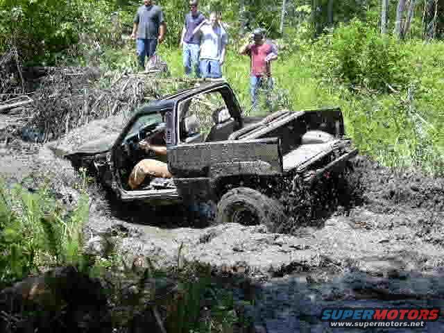 Black SUV stuck in mud with people watching