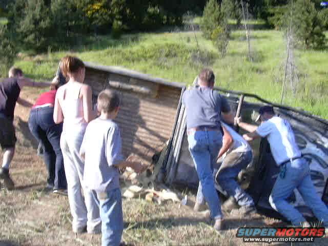 People righting a flipped 1988 Ford Bronco