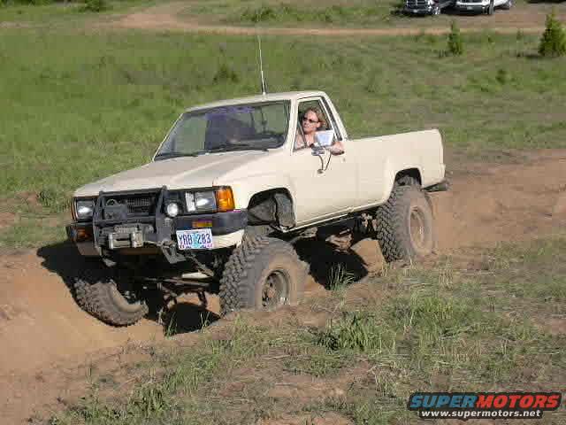 White pickup truck with off-road tires driving on a dirt hill. License plate reads YRB 283