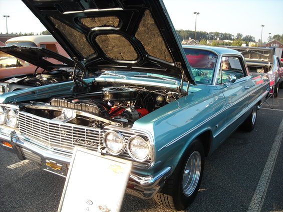 Teal 1964 Chevrolet Impala with hood open, showing engine. Another car is parked next to it