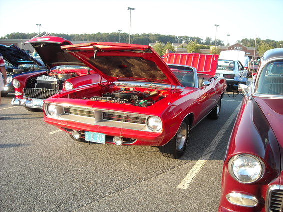 Red 1970 Plymouth Barracuda convertible with hood open, parked next to other cars at a show