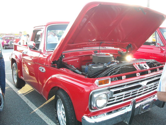 Red pickup truck with hood open, showing engine. Ford badging visible