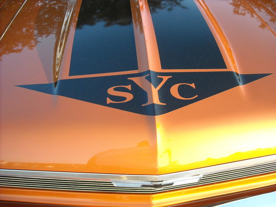 Orange car hood with black racing stripes and "SYC" text on it