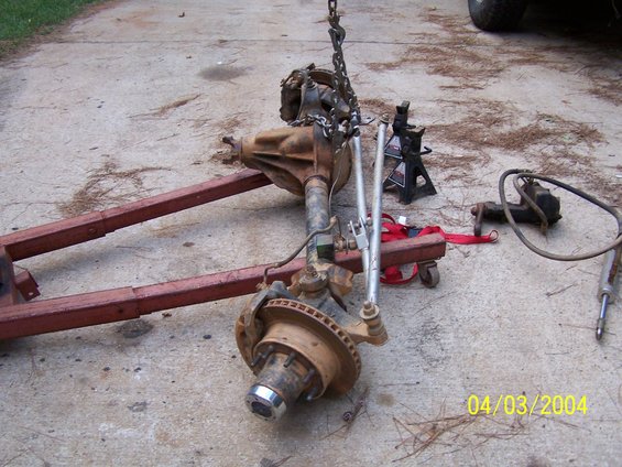 Front axle assembly with disc brakes, suspended by chains and resting on a red frame dolly