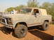 1992 Ford Bronco - A person cleans the windshield of a lifted, off-road SUV with a light-colored camper shell.
