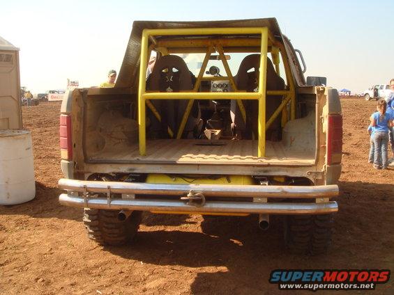 Modified Ford Bronco rear view, showing roll cage, racing seats, and custom bumper. Appears to be from the late 1980s