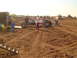 1992 Ford Bronco - People and vehicles at a mud bog racing event with a trailer and construction equipment visible.